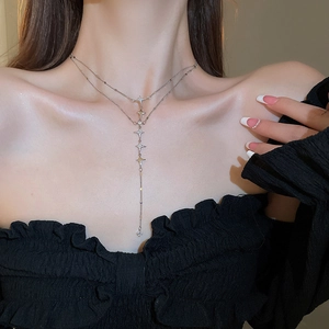 Close-up of a silver double-layered Y-shaped necklace with star pendants on a collarbone