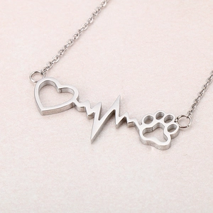 Macro shot of silver stainless steel necklace with heart, heartbeat and paw print pendant