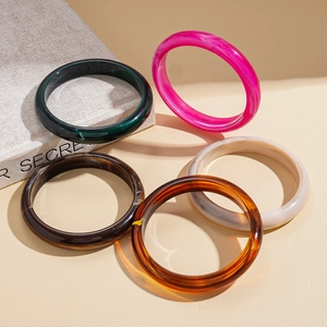 Five-piece vintage acrylic resin bangle set in mixed marble colors on a beige stand