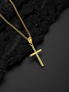 Pendentif croix doré avec chaîne gourmette présenté sur un socle en bois de charbon noir