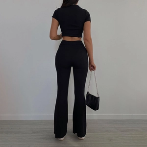 Vista posteriore del set in maglia nera con crop top a coste e pantaloni a zampa