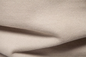 Vue macro du tissu en maille abricot montrant la texture fine et le coton doux détaillé