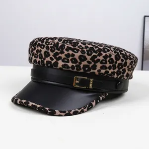 Detail of leopard print baker boy hat featuring black leather brim and golden buckle