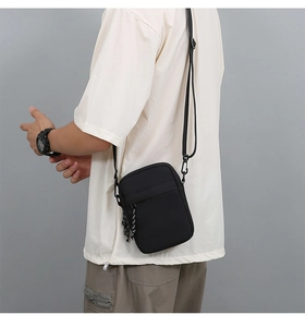 Detail of black oxford cloth crossbody bag featuring adjustable strap and woven zipper puller