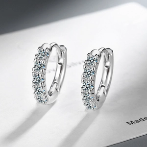 Minimalist silver hoop earrings with sparkling green zircon stones on white background