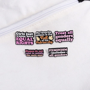 Detail von fünf feministischen Emaille-Pins mit Slogans auf weißem Canvas-Hintergrund