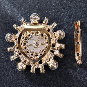 Detailed back view of a luxury pearl brooch with gold alloy base and safety pin fastener