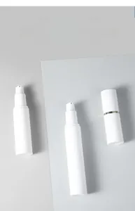 Close-up of minimalist white airless pump bottles with elegant gold ring detail accents