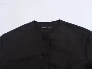 Close-up of black quilted jacket neckline with brand label and size tag S made in Morocco