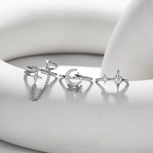 Detail view of silver star and moon rings with sparkling crystals on white geometric props