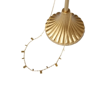 Minimalist gold titanium necklace with rectangular pendants on elegant shell stand