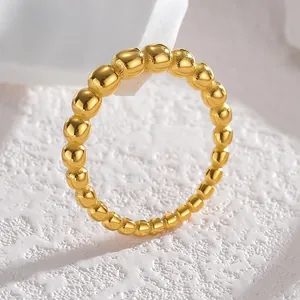 Macro view of a high-polished golden beaded ring displayed on a white textured stone