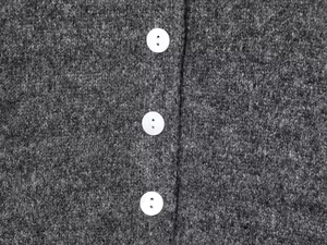 Détails macro d'un gilet en tricot gris foncé avec des boutons en nacre blanche