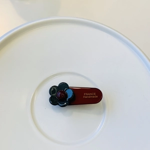 Handmade French style hair clip with dark blue flowers on deep red base in a white tray