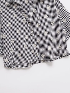 Détail de chemise à carreaux manches courtes avec broderie florale blanche