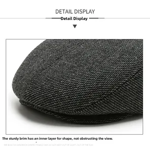 Detail view of the sturdy curved brim on a gray textured woolen newsboy cap for men