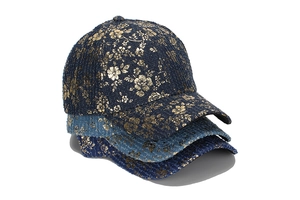 Tre cappellini da baseball in tweed blu con motivi floreali dorati impilati su sfondo bianco