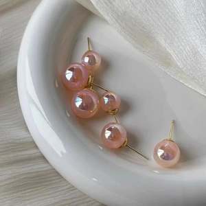 Elegant pink mermaid pearl earrings in various sizes on a white ceramic display plate