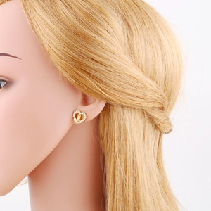 Macro shot of gold heart-shaped earrings featuring zircons and Virgin Mary relief