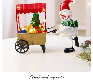 Detailed view of metal Christmas snowman trolley with LED lights and gift box decor