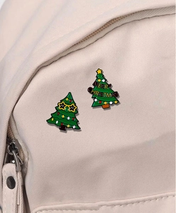 Detail of Christmas tree enamel pins with star glasses and Merry Christmas text on a bag