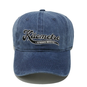 Detail of Kilometre embroidery on a washed navy blue cotton baseball cap with vintage finish