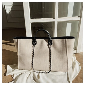 Detail of canvas tote bag with black leather trim and silver metal eyelets for shoulder strap