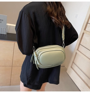 Model view of a light green textured leather crossbody bag with a wide strap