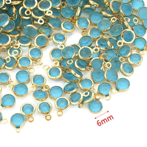 Macro detail of 6mm blue crystal birthstone pendants with gold stainless steel frames