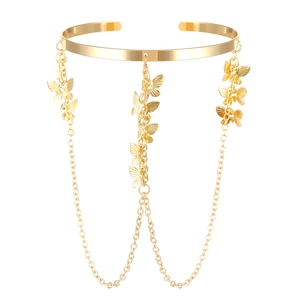 Macro detail of gold arm cuff with layered chains and textured butterfly charms