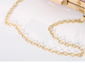Macro shot of polished gold metal chain strap for women's elegant evening clutch bag