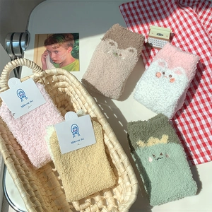 Close-up of thick coral fleece socks with cute cartoon embroidery and fluffy texture