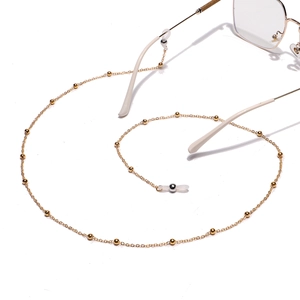 Golden metal beaded eyewear chain with white silicone loops shown with gold glasses