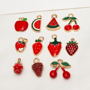 Flat lay of 11 red and green enamel fruit alloy charms for DIY jewelry making