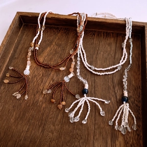 Macro detail of bohemian beaded tassel necklaces displayed on a rustic wooden tray