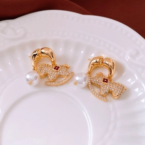 Détail macro d'une boucle d'oreille cheval à bascule 18K avec cristaux et perle