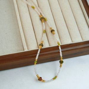 Detail of beaded necklace with natural pearls and green crystals on velvet display