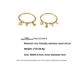 Close-up of golden stainless steel bangles with bear and elephant zircon pendants
