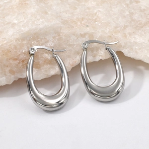 Close-up of polished silver U-shaped hollow earrings on a natural stone background
