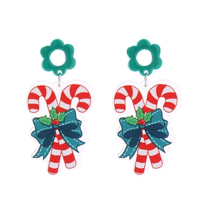 Close-up of Christmas candy cane earrings with green bows and red berry accents