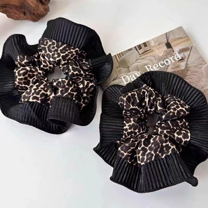 Detail of two-piece leopard print and black pleated scrunchies set on white desk