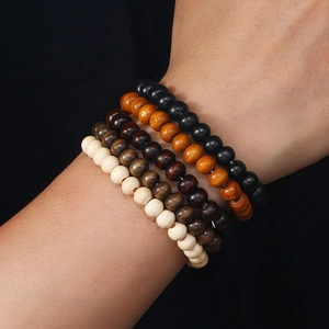 Close-up of stacked handmade wooden beaded bracelets in black and brown on a wrist