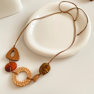 Vue détaillée d'un pendentif en rotin et résine sur une assiette en céramique minimaliste