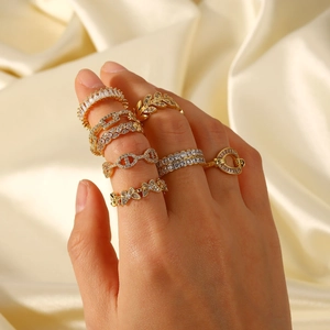 Selection of assorted 18K gold plated copper rings with zircon inlays on beige silk fabric