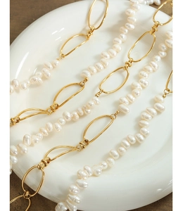 Close-up of Baroque freshwater pearls and golden oval chain links on a minimalist necklace