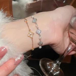 Elegant gold clover bracelet with pearls and zircon crystals shown on a wrist