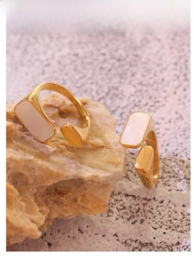 Detailed close-up of 18K gold plated titanium rings with white shell inlays on stone