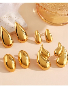 Macro view of gold stainless steel teardrop and flame earrings with polished finish