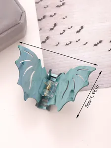 Detail of bat-shaped Halloween hair claw clip with dark teal marble texture and metal spring