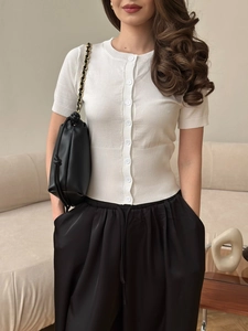 Cardigan corto in maglia bianca da donna abbinato a pantaloni neri a gamba larga elegante